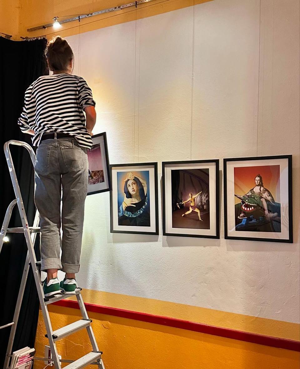 Ein Foto von einer Frau, die auf einer Leiter steht und ein Bild an die Wand hängt.